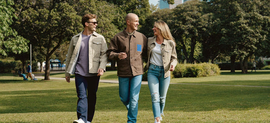 Three young adults share a cheerful conversation during a park walk