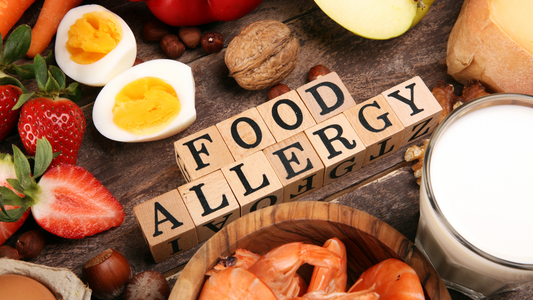 Food allergy concept with wooden blocks spelling food allergy surrounded by common allergenic foods like nuts, milk, eggs, strawberries, shrimp, and cheese