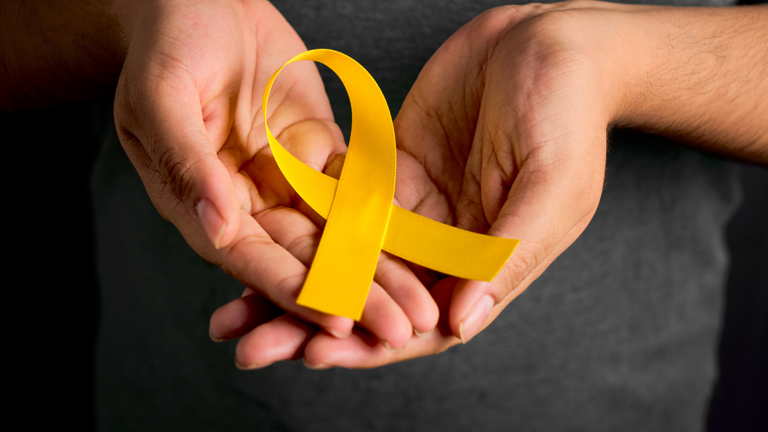 Hands holding a yellow cancer awareness ribbon symbolizing Cancer The Real Facts awareness and support