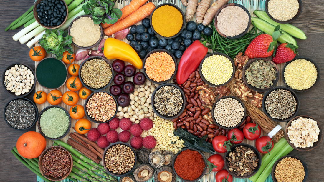 Assorted superfoods for gut health including seeds, berries, nuts, spices, and vegetables arranged on a wooden surface