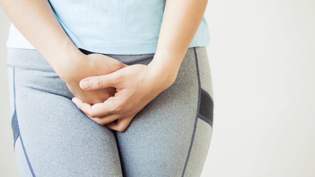 woman holding lower abdomen wearing gray pants illustrating yeast infection treatment tips