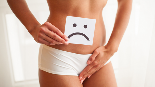 woman holding sad face sign over lower abdomen representing signs your vagina is unhealthy