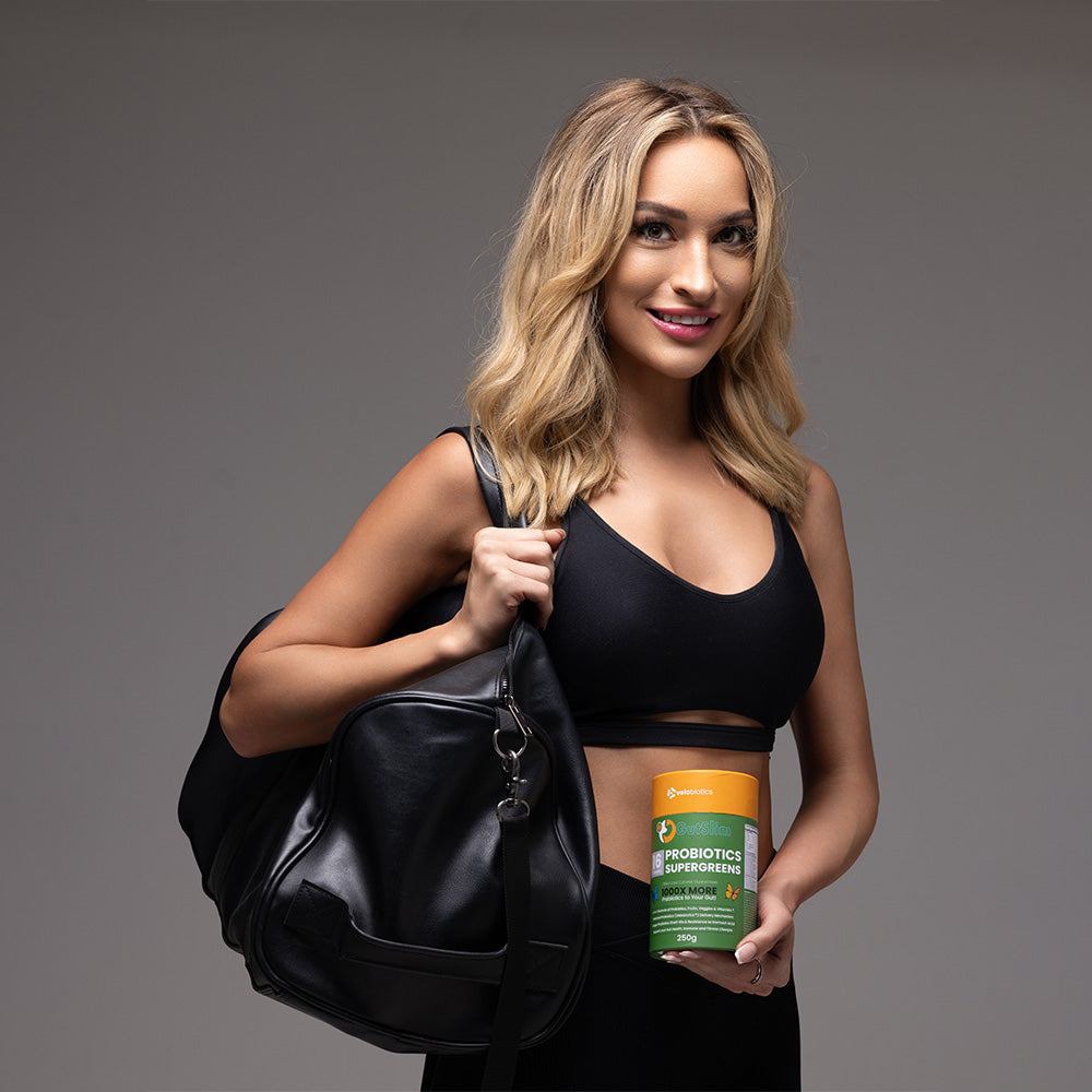 woman holding GutSlim Probiotics SuperGreens container with gym bag, promoting gut health and energy benefits