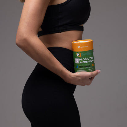 Fit woman holding GutSlim Probiotics SuperGreens container promoting gut health and digestion support