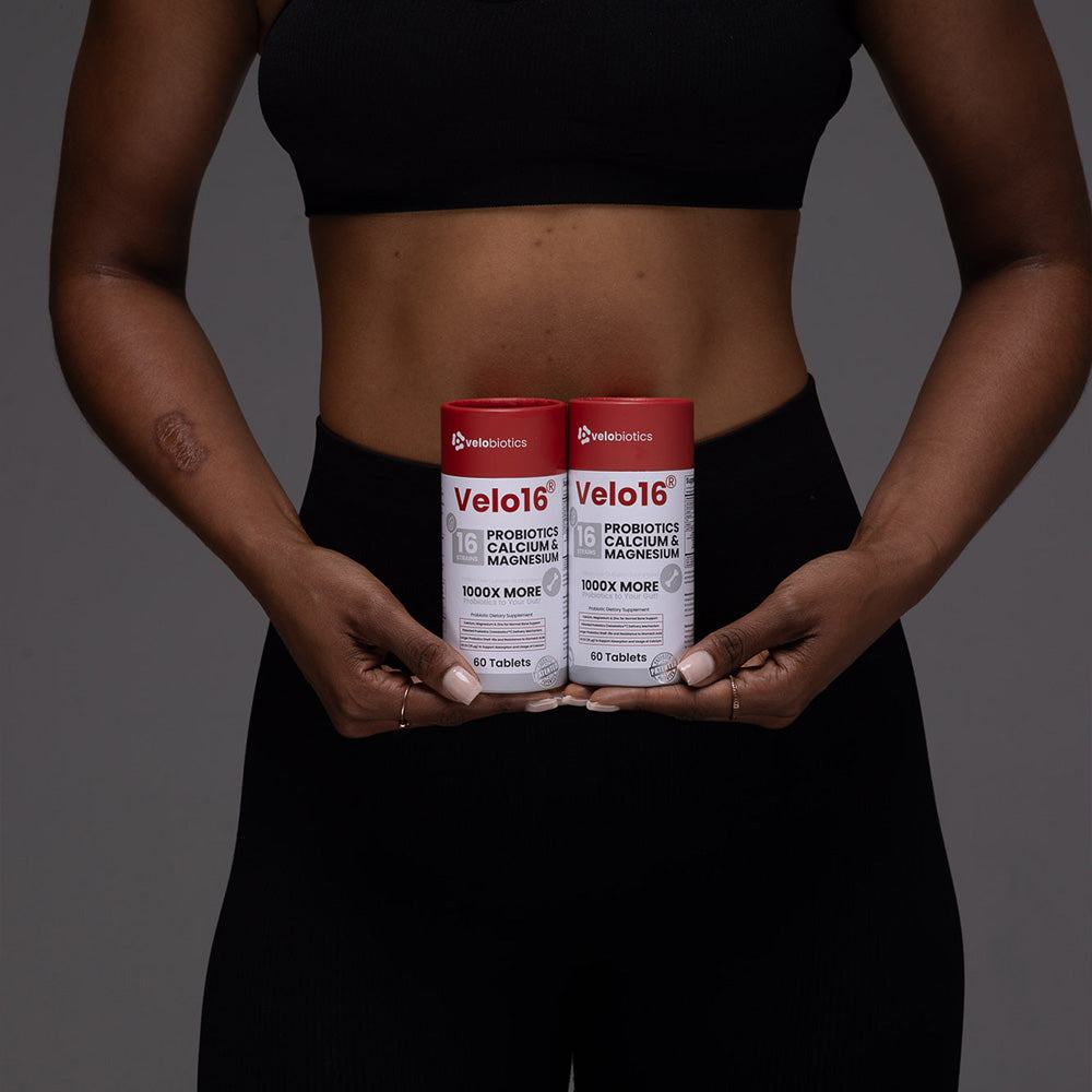 Velo16 Probiotics Calcium & Magnesium supplement bottles held by person promoting gut and bone health