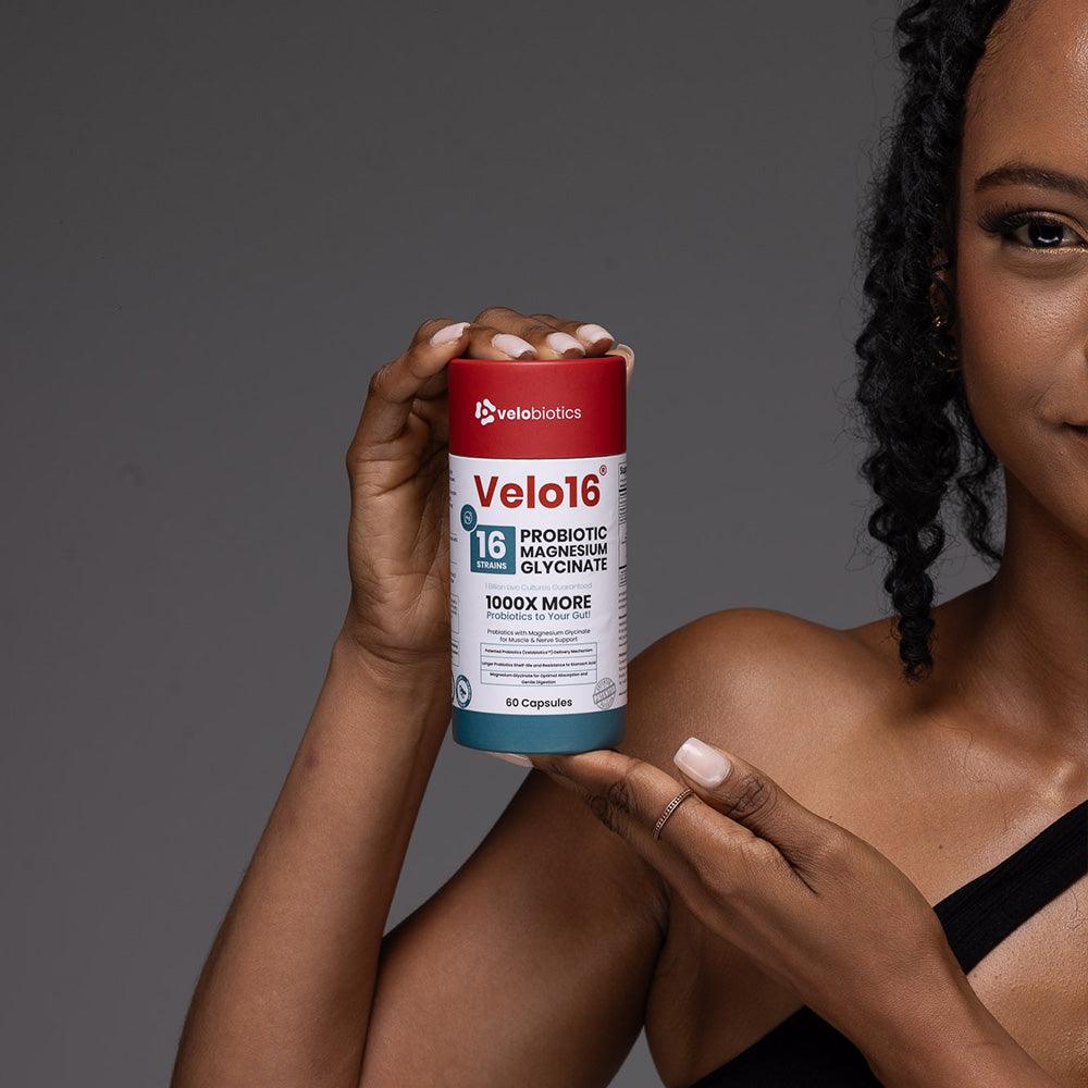 Velo16™ Probiotics Magnesium Glycinate supplement bottle held by woman promoting gut health and relaxation