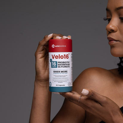 Velo16 Probiotics Magnesium Glycinate supplement bottle held by person promoting gut health and muscle relaxation