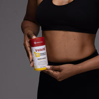Person holding Velo16™ Probiotics Vitamin D3 supplement bottle for gut and immune health.