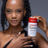 Woman holding Velo16 Probiotics + Ashwagandha Complex supplement bottle promoting gut health and stress relief