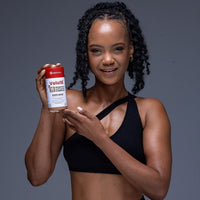 Woman in black sportswear holding Velo16™ Probiotics + Ashwagandha Complex supplement bottle promoting gut health and stress relief
