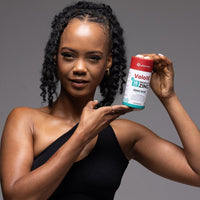 Woman holding Velo16 Probiotics + Zinc Picolinate supplement bottle promoting gut and immune health